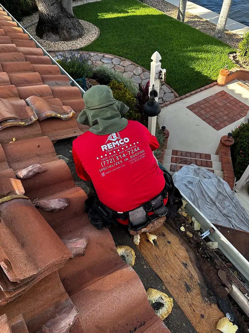 Remco roofer in a branded red shirt removing old tile