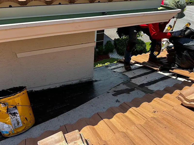 Crew working on an exposed roof deck after tile tear-off